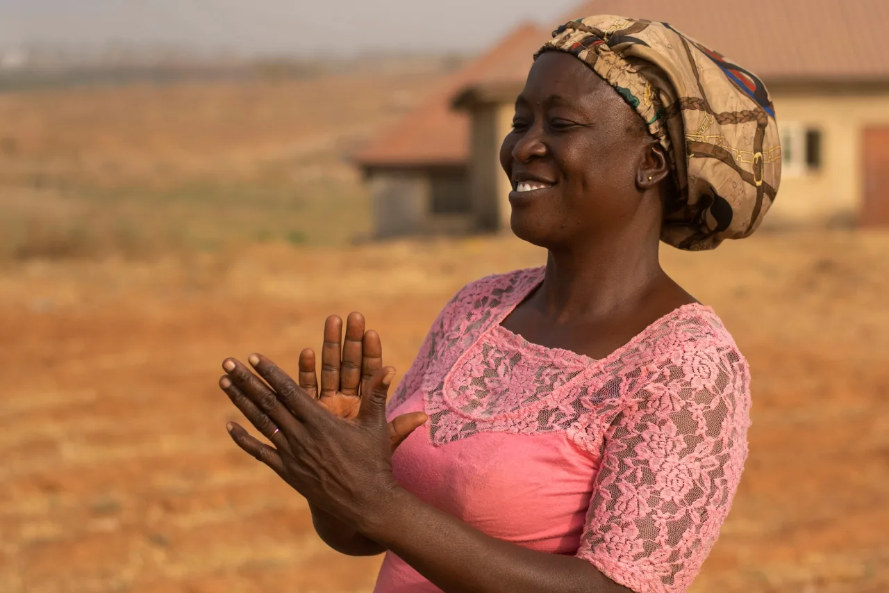 A smiling woman outdoors with her hands together