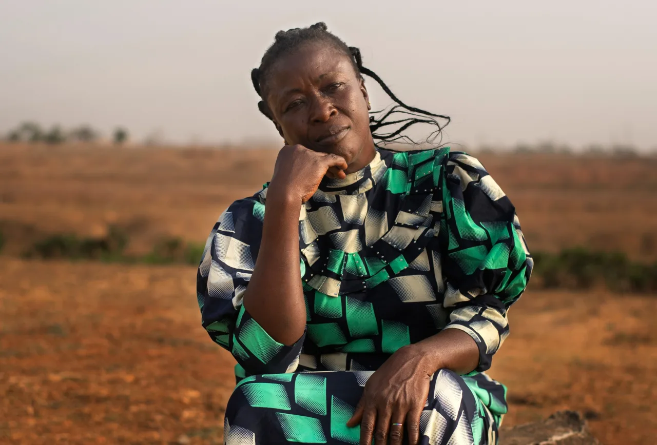 A woman seated in an open rural landscape